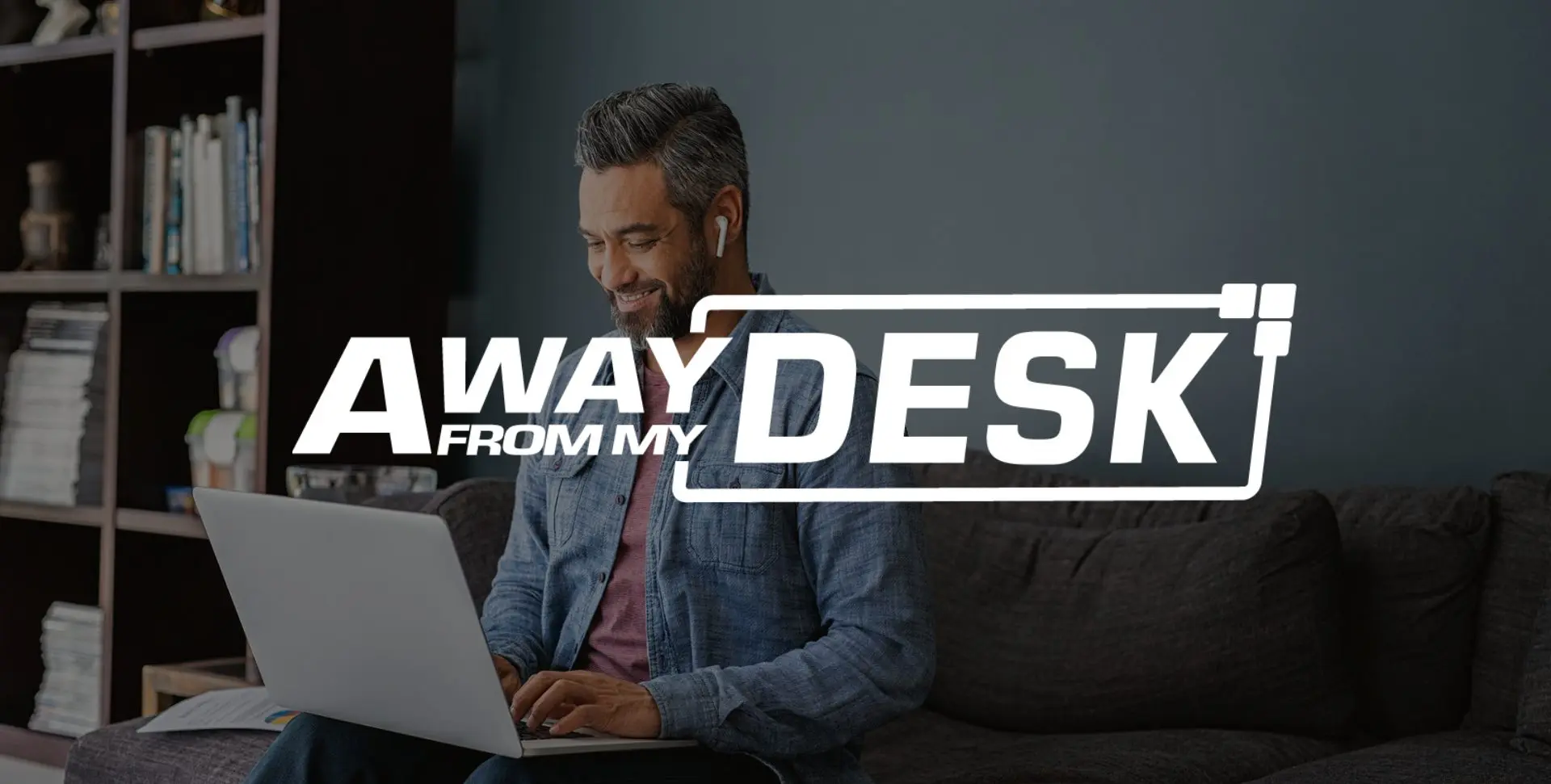 AwayFromMyDesk white logo on a background with a smiling man sat on a sofa at home, whilst working on his laptop