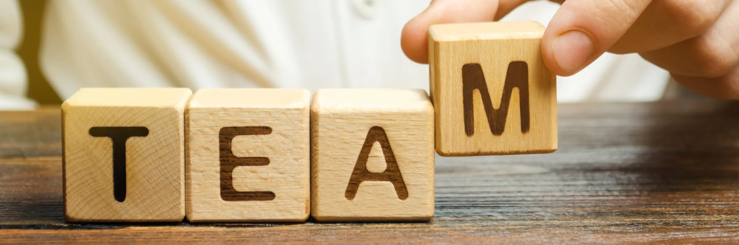 person positioning wooden blocks to create the word Team.