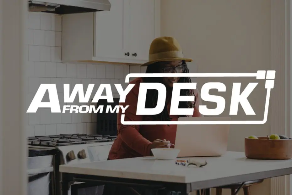 Woman working on her laptop in her kitchen with the away from my desk sign on top of it