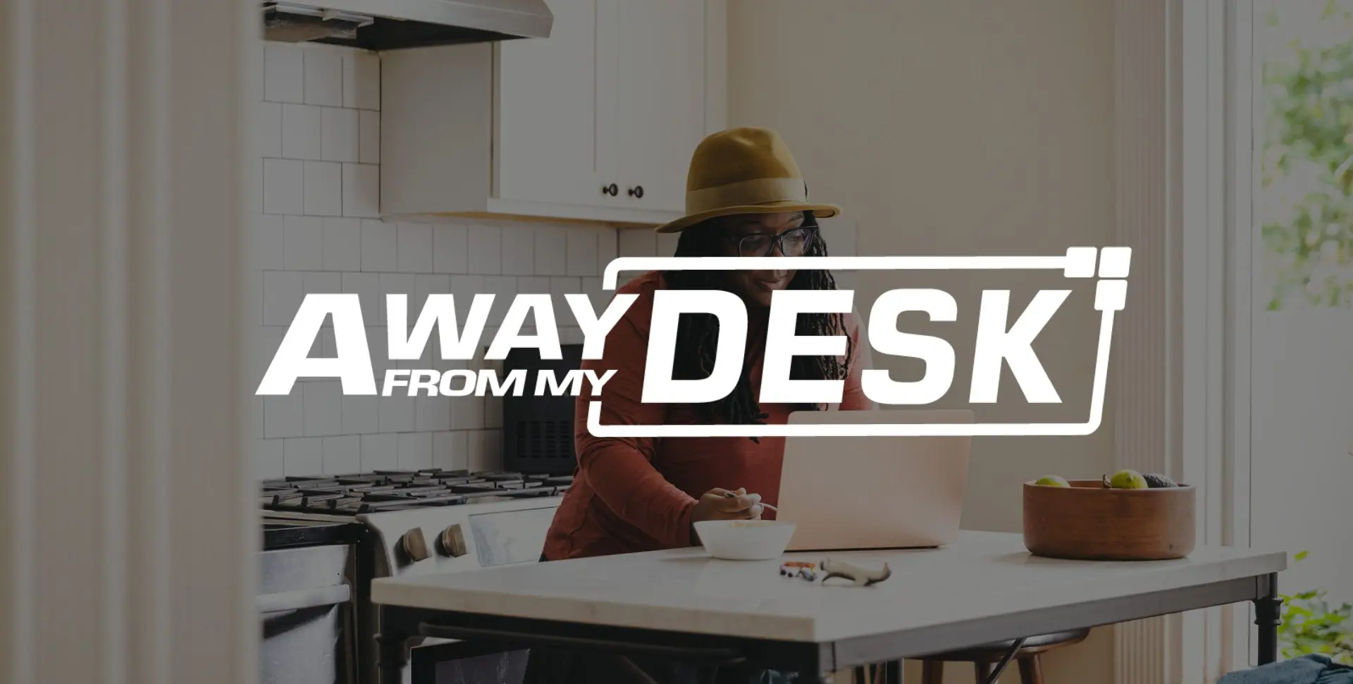 Woman working on her laptop in her kitchen with the away from my desk sign on top of it