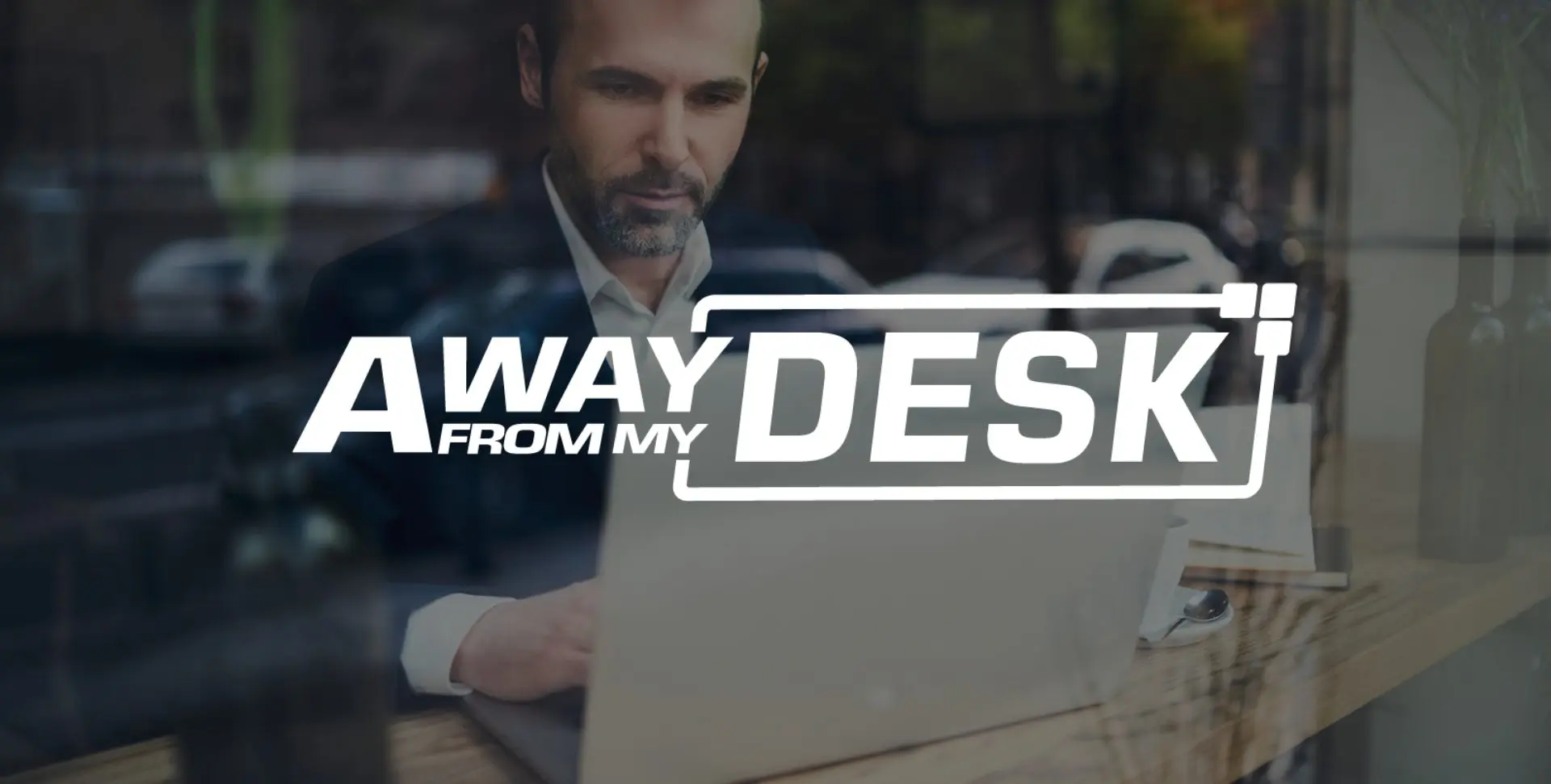 man in a suit looking at his computer with the Away From My Desk logo on top of it