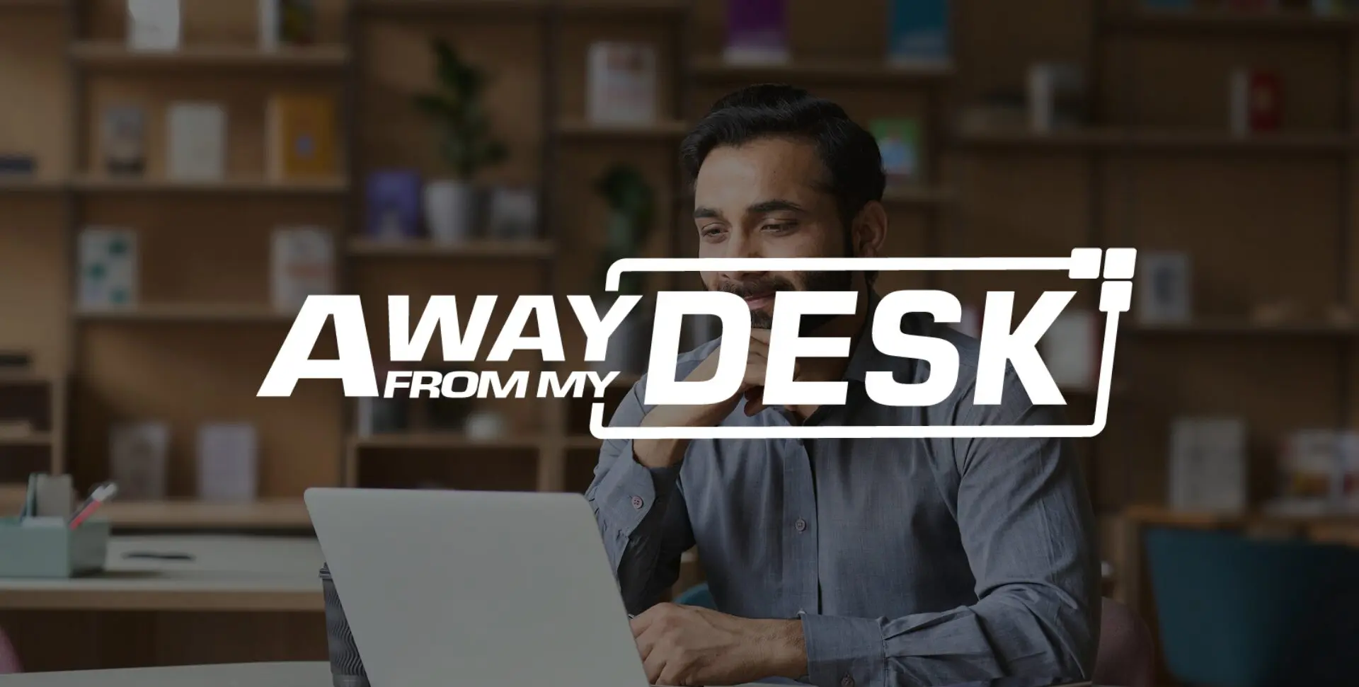 Man smiling at a laptop with the Away From My Desk logo on top of it