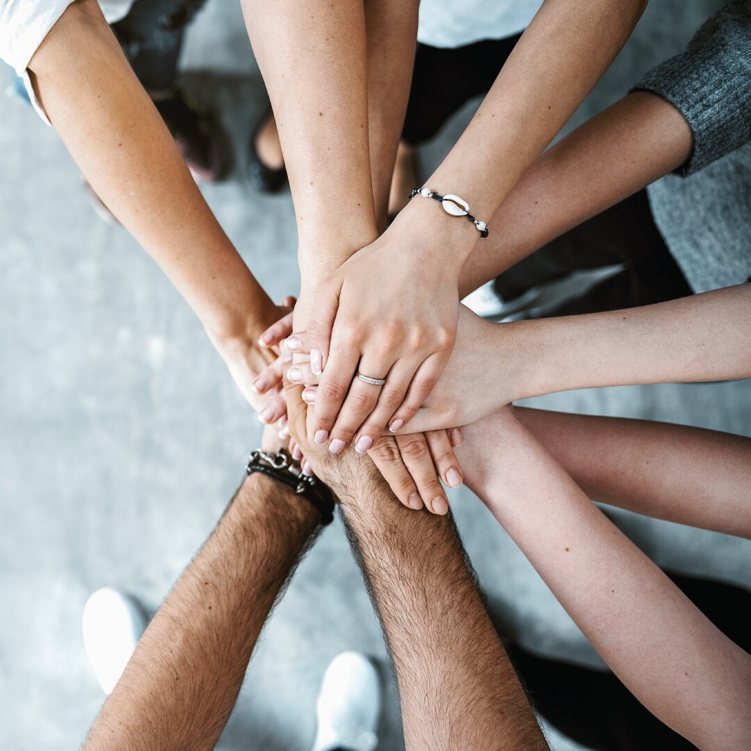 Group of people with their hands piled together to show a successful and grouped working environment
