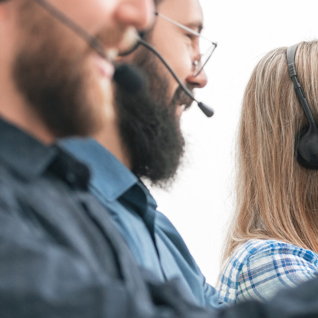 Two men and one woman, each wearing headsets, providing remote support to customers