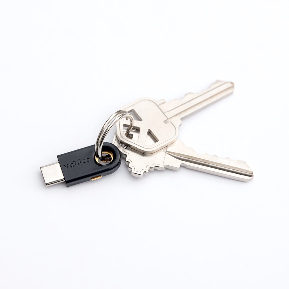 YubiKey 5c token on a keyring with two keys, on a white background