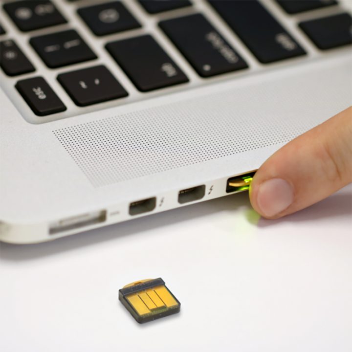 Yubikey 5 nano token on surface next to a laptop