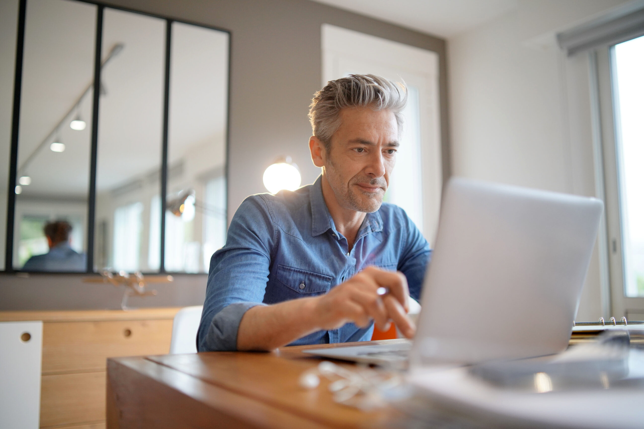 Mature man working from home on his laptop sat at the table